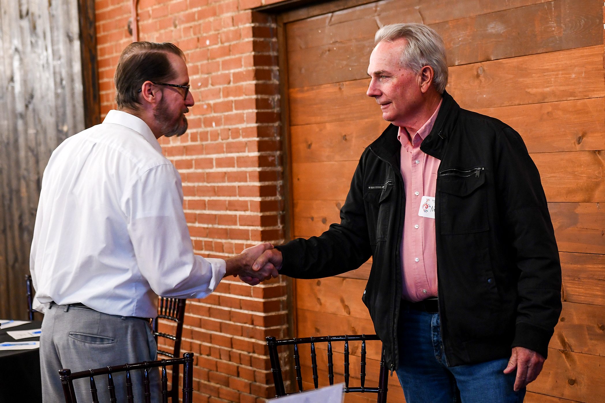 An attorney greeting a client at the brick wall at the firm's 2026 annual client meeting