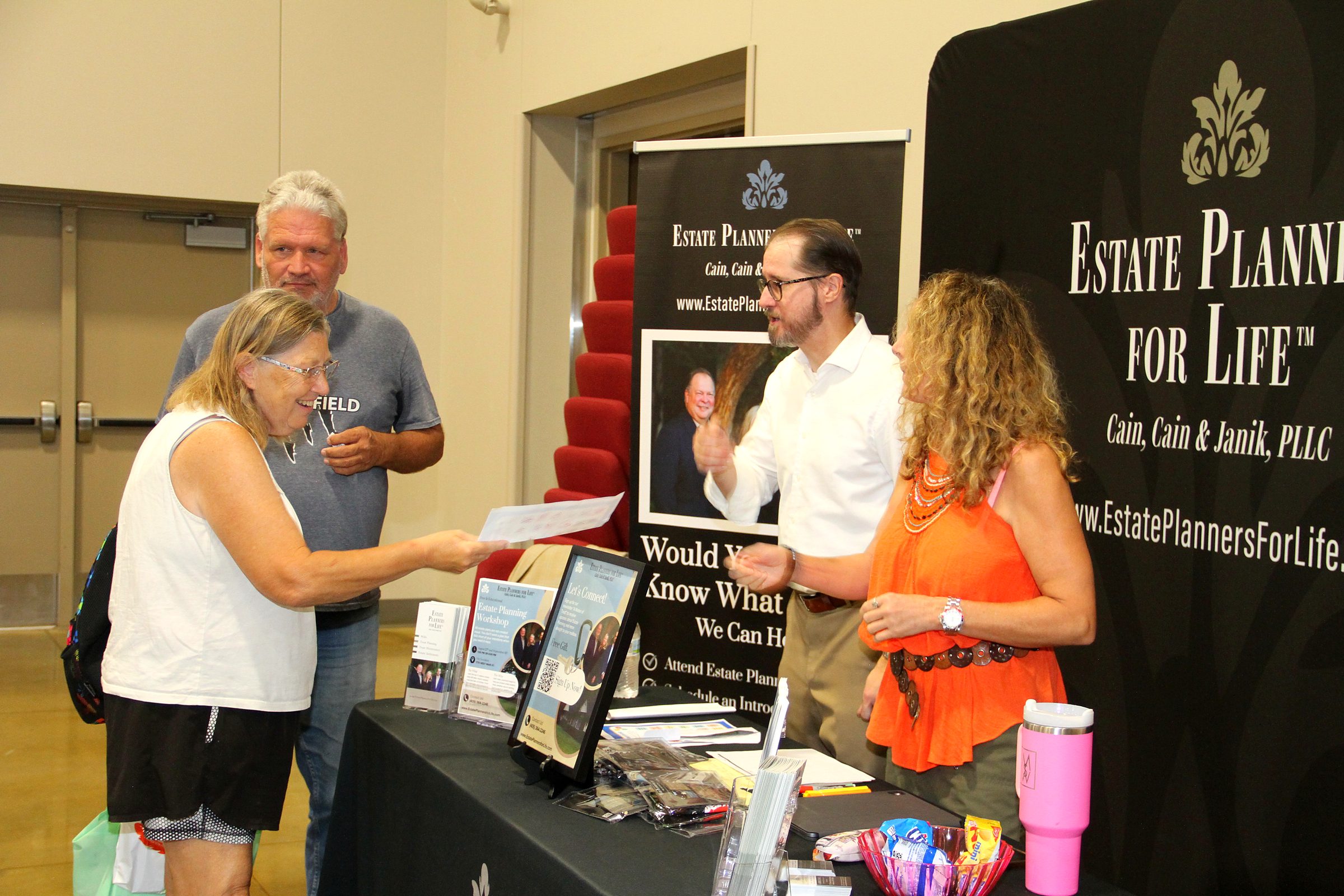 Mitch Janik and a member of the team talking with visitors at the firm's booth at a community senior expo