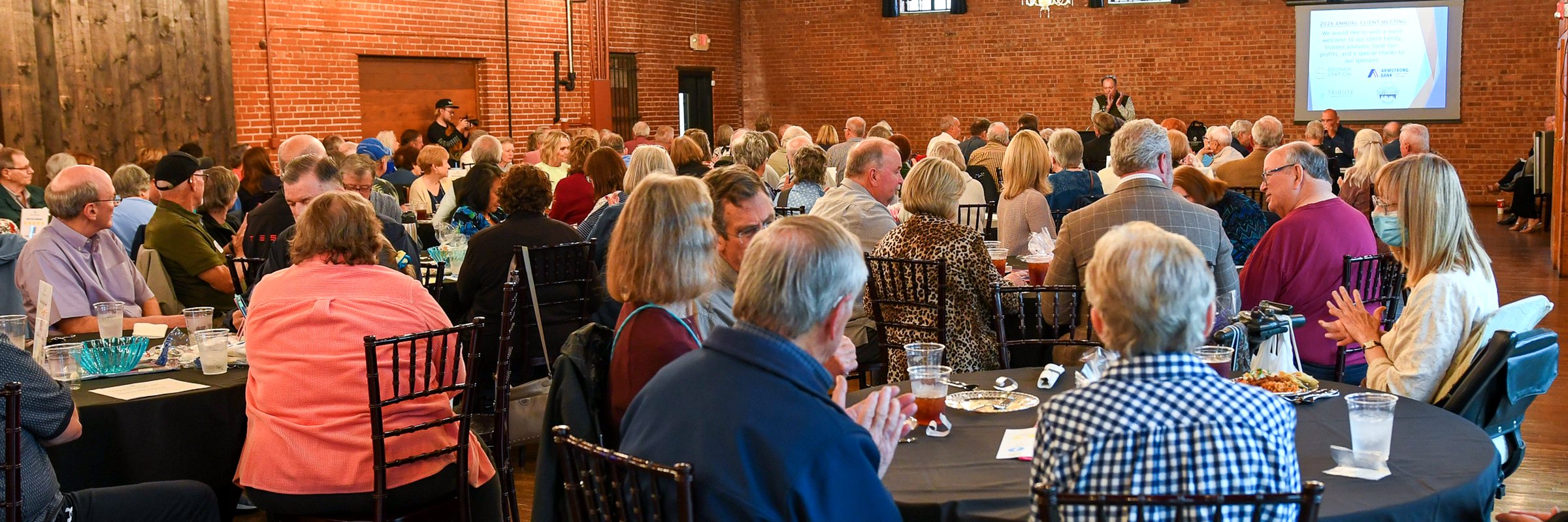 The room at the firm&rsquo;s 2026 annual client meeting, exposed brick and string lights