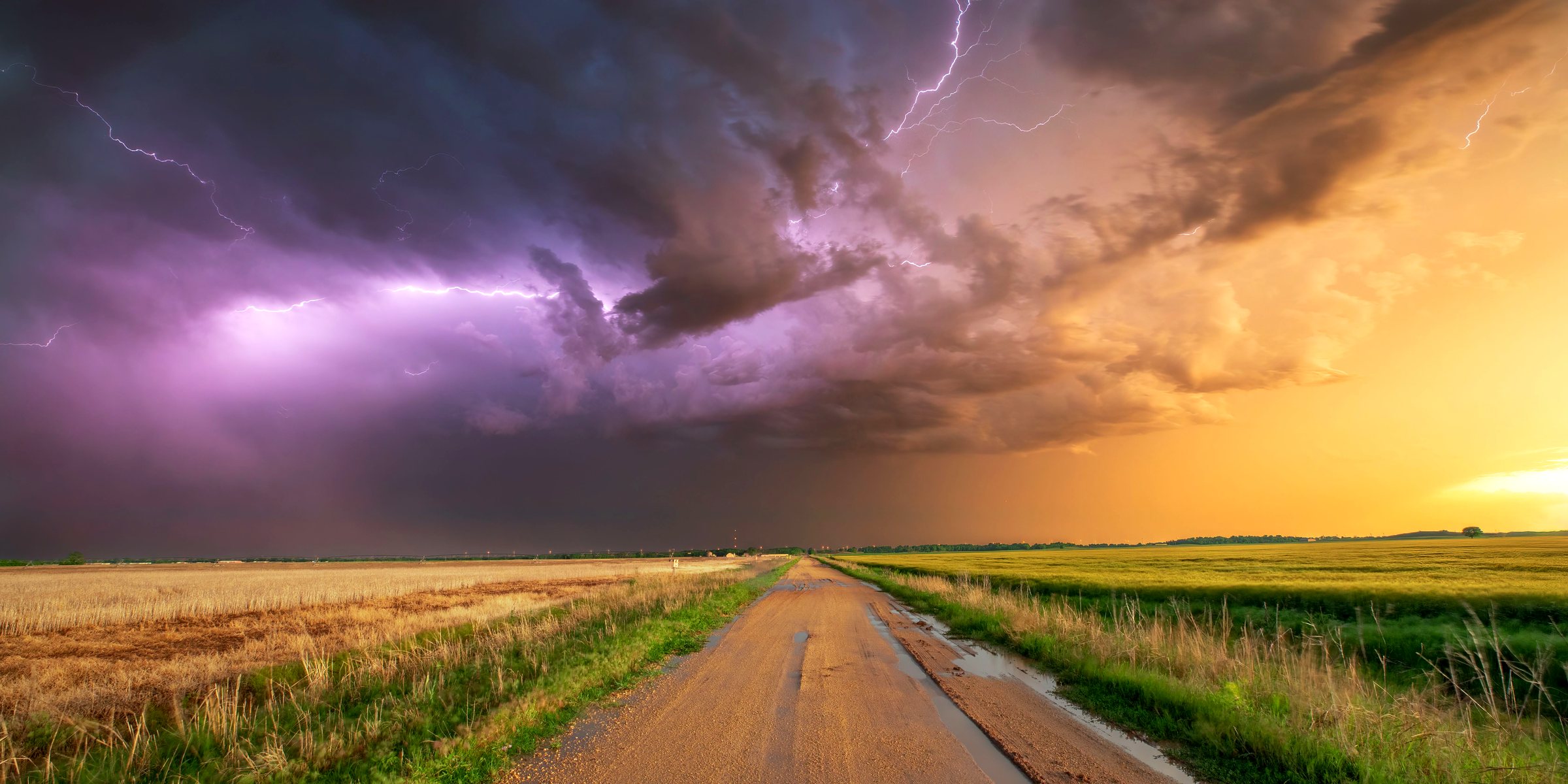 A storm crossing open farmland at sunset